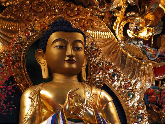 Gilded metal statue of preaching Buddha in a Tibetan Buddhist monastery in Sarnath