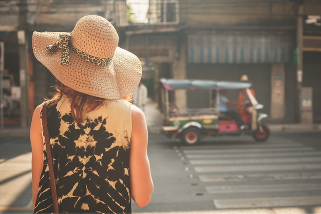 A young woman wearing a hat is walking in the streets of an asian countryA young woman wearing a hat is walking in the streets of an asian country