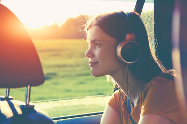 smiling pretty girl listening to music with headphones moving in car