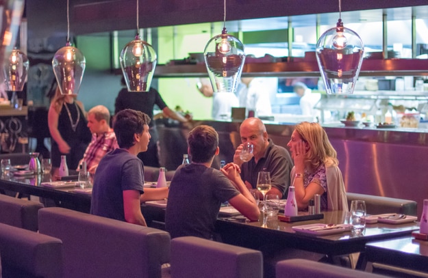 People having dinner in a modern and chik open kitchen restaurant in Israel. Part of the hip Sarona district featuring restored Templer buildings