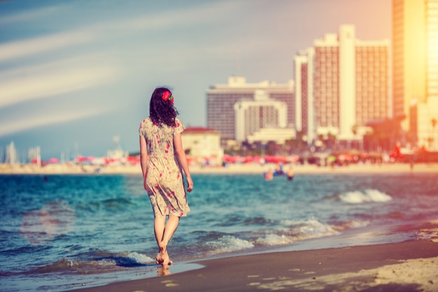 Young woman walking back to camera at sunset on the beach in Tel Aviv, Israel