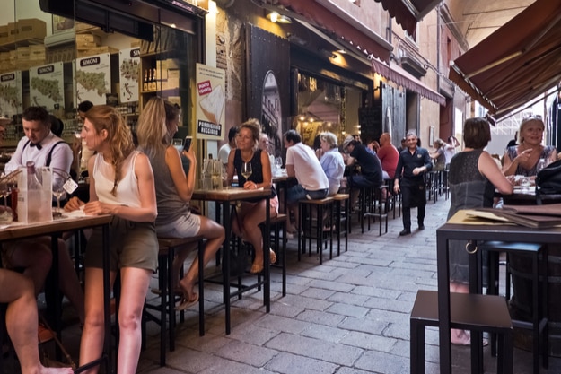 People enjoy an aperitif, eating and drinking traditional foods in Bologna, Italy