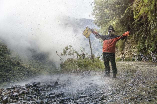 Bike adventure travel photo. Bike tourist on the road of death enjoys the waterfall