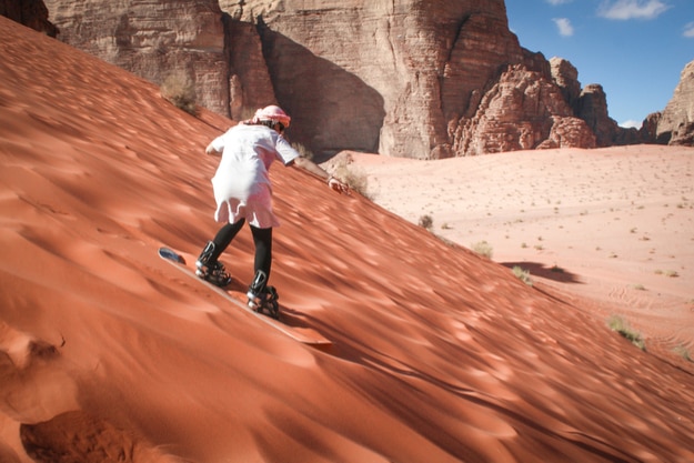 Girl sand boarding on dunes in Wadi Rum