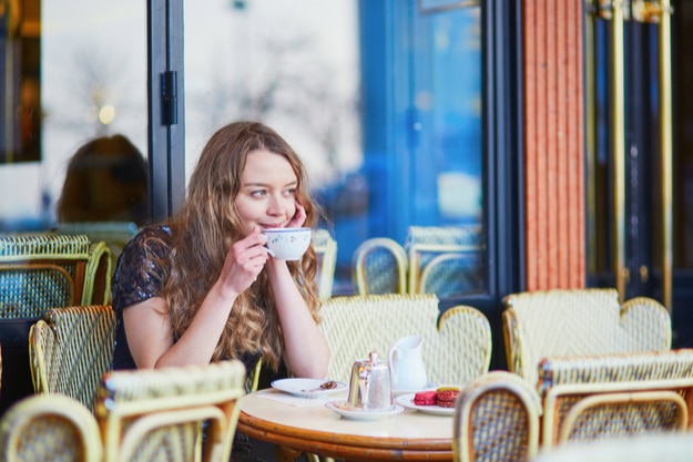 Parisian woman in cafe, drinking coffee and eating macaroons, traditional French dessert