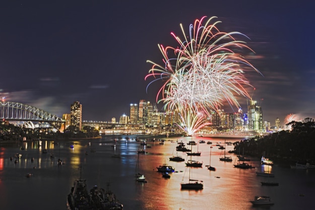 Multi colour light balls during new year fireworks in Sydney city CBD elevated view over blurred harbour waters towards Harbour bridge and Sydney Landmarks