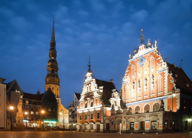 Beautiful old architecture of the central square of Riga. Night view with blue cloudy sky in background and illuminated buildings in foreground