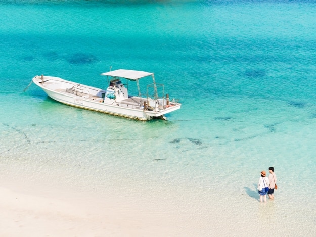 Boat and a couple in the summer at Kabira bay beach, Ishigaki Island (Ishigakijima), Okinawa, Japan. A scenic spot representing Okinawa