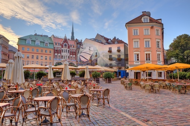 Cobbled city square with outdoor restaurants among colorful buildings in Riga