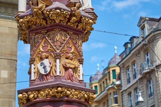 Detail of the medieval fish market fountain with the crest of Basel and a lute player, in Basel downtown