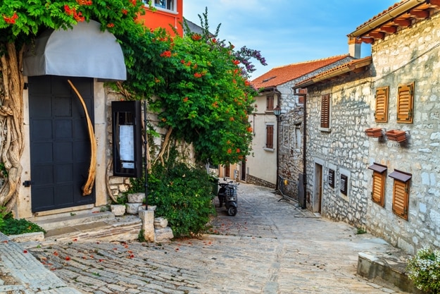 Spectacular stone paved street and restaurant entrance with colorful mediterranean flowers, Rovinj old town,Istria region,Croatia,Europe