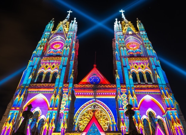 The neo - gothic style Basilica of the National Vow (Basilica del Voto Nacional) illuminated with colorful lights during the Quito light festival
