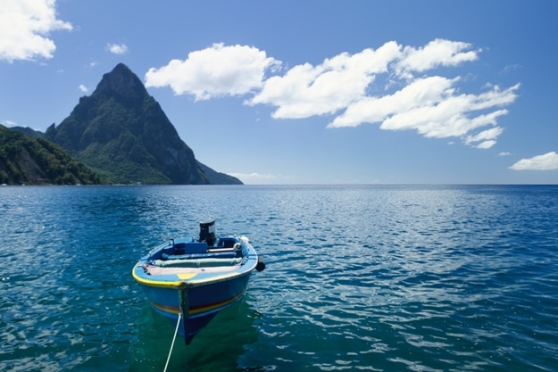 A small blue boat on a beach in St Lucia with Petit Piton in the background