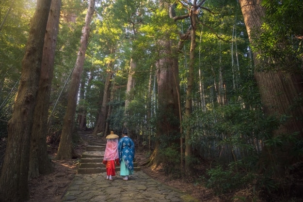 Pilgrim man and woman are hiking up the Daimon-zaka. The route, paved with stone and lined with massive evergreens, leads 600 meters up to the the gates of Nachi Taisha, Wakayama, Japan