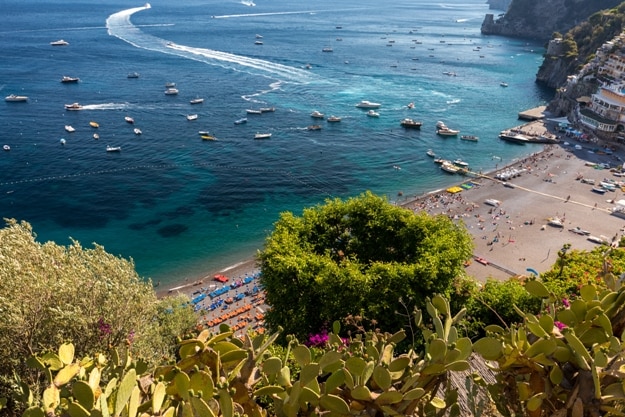 The main beach in Positano, Spiaggia Grande, with its bright orange and blue beach umbrellas and the sparkling blue sea of the Amalfi Coast